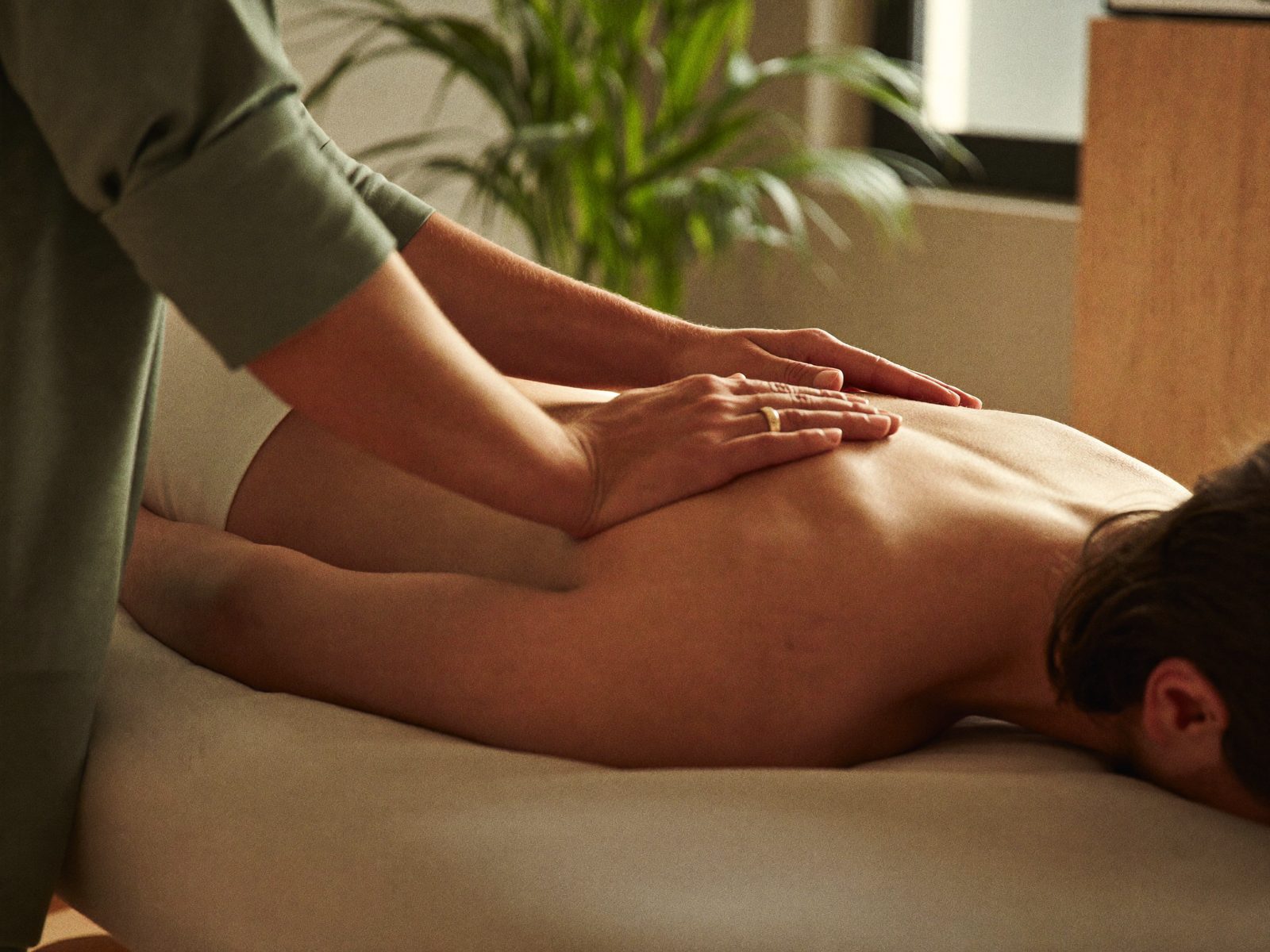 Manos de un fisioterapeuta tratando la zona lumbar de un paciente